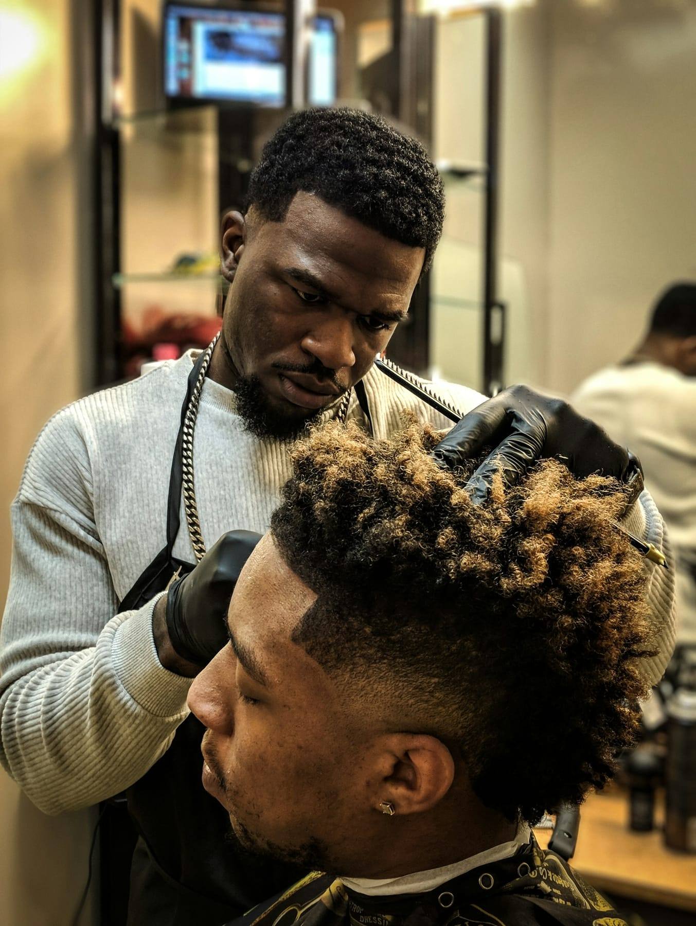 Barber shaping a textured curly cut with clippers
