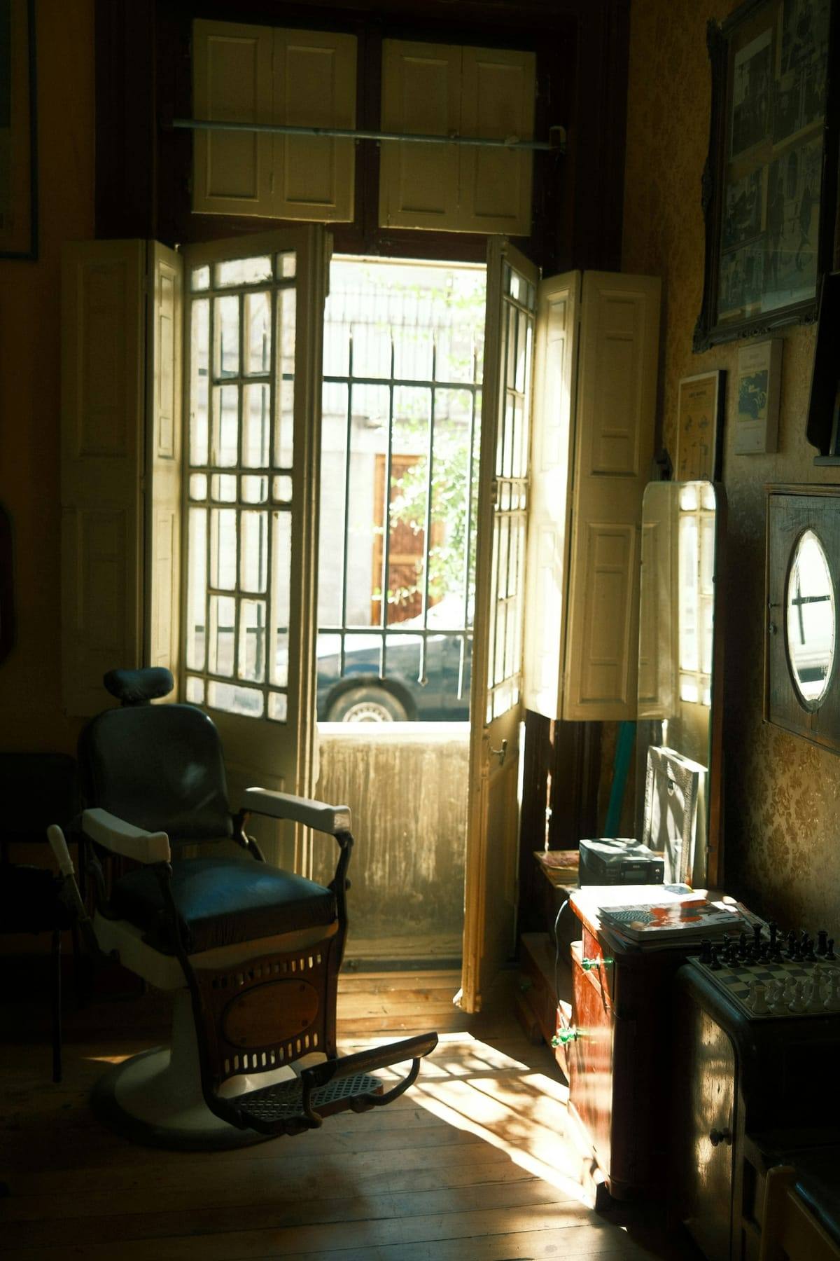 Vintage barber chair in warm afternoon light beside tall windows